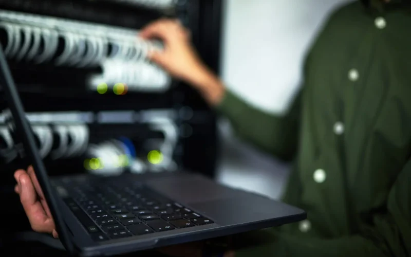 Server room maintenance, laptop and technician at work for cyber security and building network. Pro.